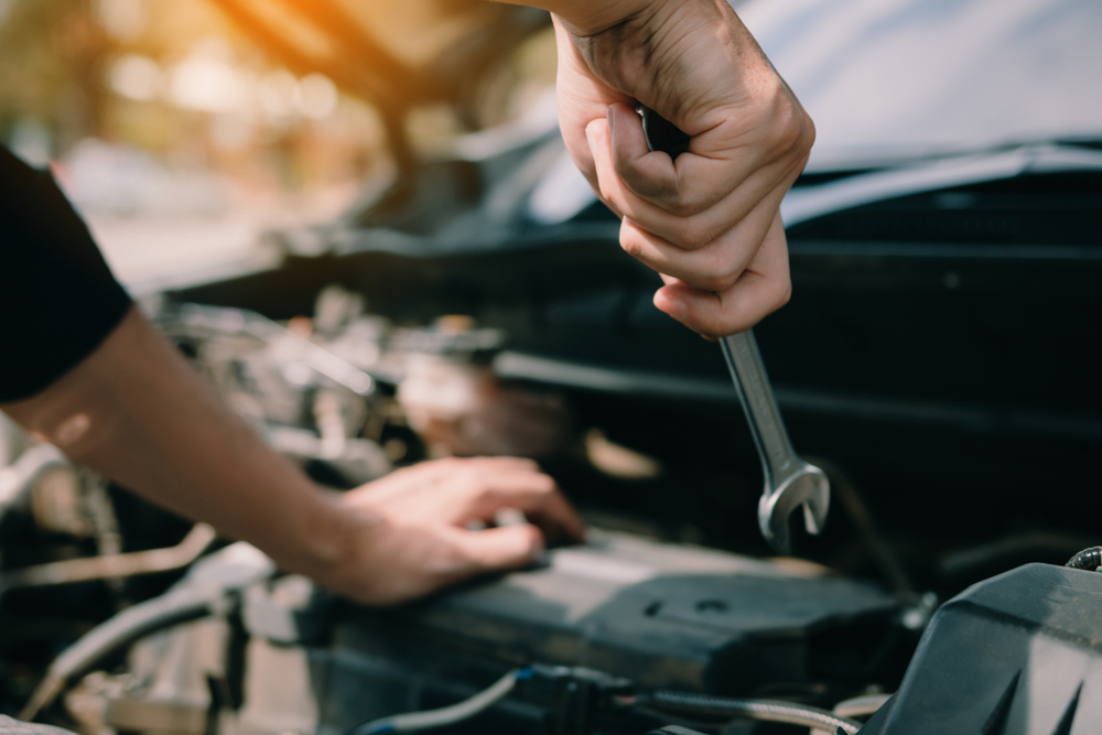 Mechanic repairing common used car component faults using hand tools in workshop