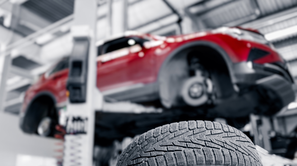 Red car raised on ramp in an independent workshop during a tyre inspection for XtraCOVER protection