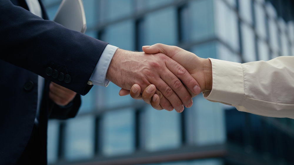 Business partnership handshake outside modern premises symbolising the WSG and AutoXtraPro collaboration