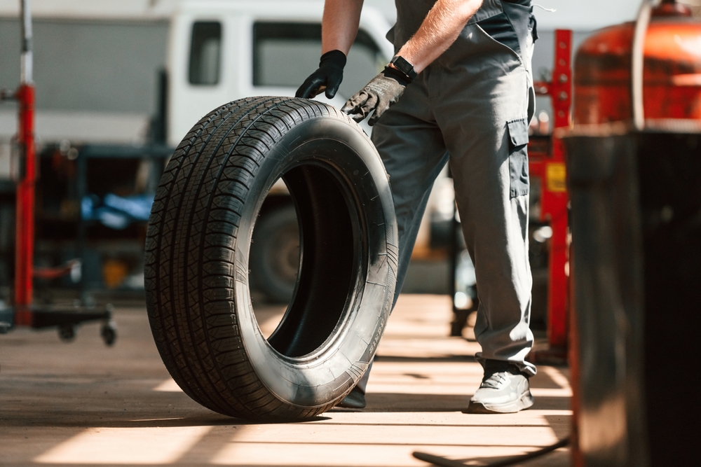 Workshop technician rolling a car tyre across an independent garage floor for XtraCOVER tyre cover fitting